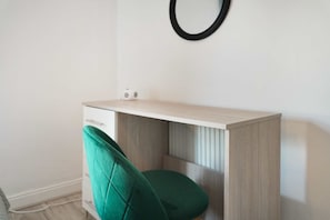 Una scrivania di legno chiara e poco ingombrante con un cassetto e una sedia verde.