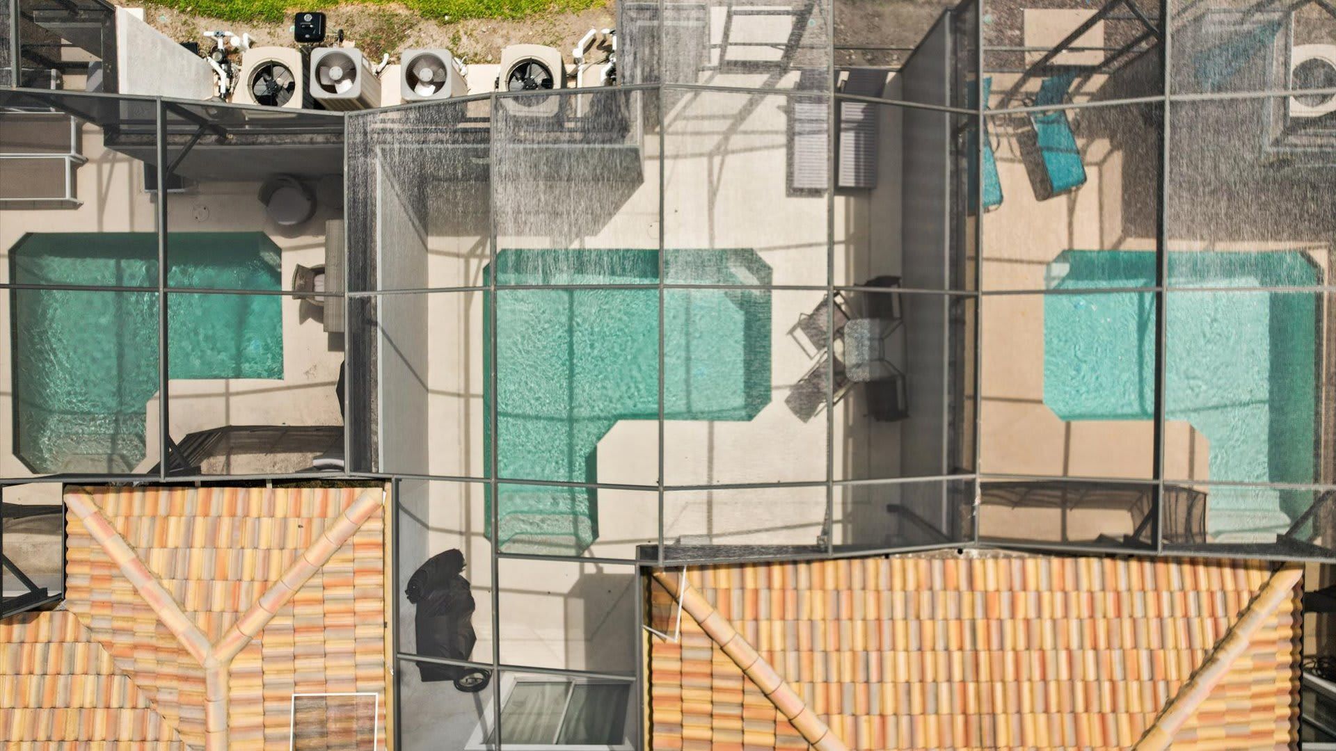 Een zwembadgedeelte met helder water, omgeven door een glazen constructie, en voorzien van meerdere airconditioninginstallaties.