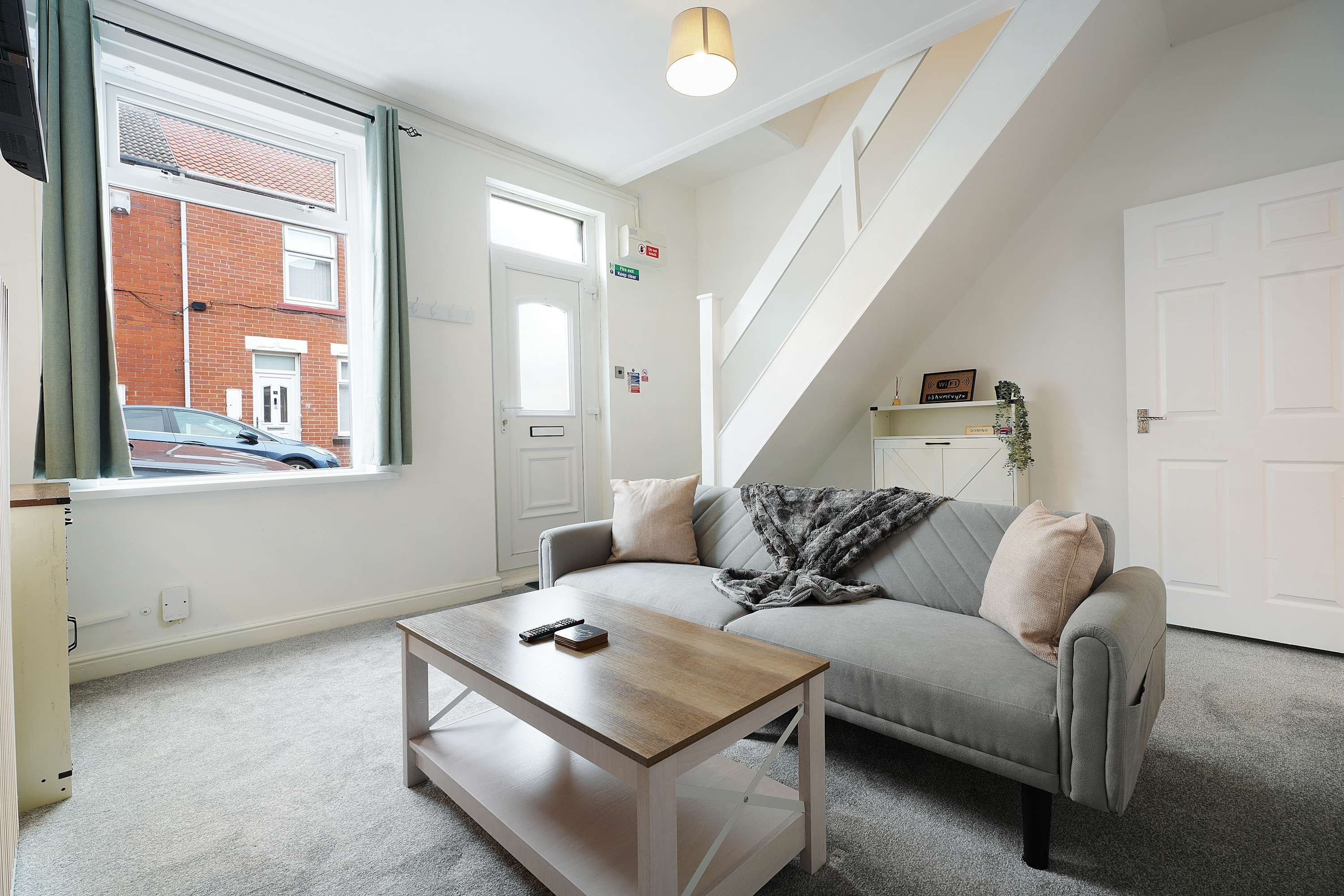 A modern living room with a sofa, a coffee table, and a staircase.