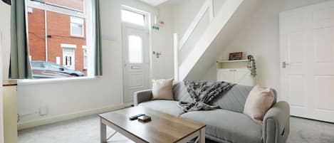 Un salon moderne avec un canapé, une table basse et un escalier.