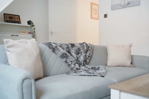 A light grey sofa with a patterned throw blanket and two pillows. - Cosy Blackhall 2BR Sleeps 5 By Stay With Us (Hartlepool)