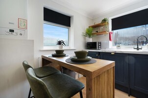Cocina moderna con una mesa de madera, dos sillas, un microondas y una ventana con vistas.