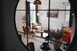 Una sala de estar con un sofá, sillones, una mesa de centro y una mesa de comedor con sillas.
