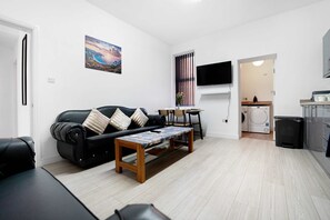 Ein modernes Wohnzimmer mit einem schwarzen Ledersofa, einem Holztisch und einem Bild an der Wand.