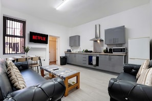 A modern apartment with a living room, kitchenette, and a TV displaying 'NETFLIX'. - Ground-floor 2BR Newcastle Retreat Sleeps 4 (Newcastle-upon-Tyne)