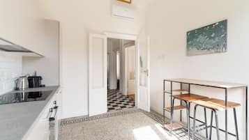 Een moderne keuken met een zwart-wit geruite vloer, een witte muur met een ingelijste foto, en een gang die naar een andere kamer leidt.