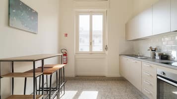 Een keuken met witte kastjes, een aanrecht, een kookplaat en een brandblusser.