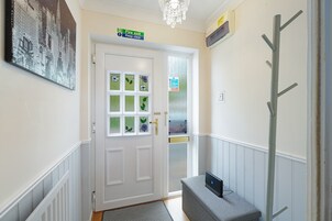 A hallway with a white door, a fire exit sign, a fire action sign, and a coat rack.