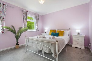 A bedroom with a bed, bedside tables, a potted plant, and a window with curtains.