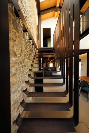 A staircase with a stone wall on one side and wooden railings on the other, leading to an upper level. - Historic Tuscan farmhouse with double-height hall (Montemurlo)
