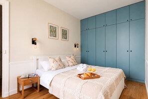Quarto com cama, mesa de cabeceira, guarda-roupa e duas luzes na parede.