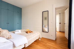 Un dormitorio con cama, cómoda, espejo y una bandeja de cruasanes.