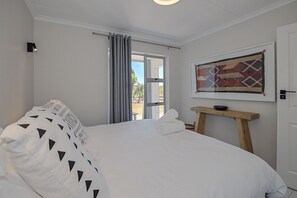 Ein Schlafzimmer mit einem Bett, einem Fenster, einer Tür und einem Wandbild.