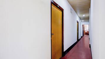 Un couloir avec des portes en bois et une moquette rouge, qui mène à une pièce dotée d’une fenêtre.