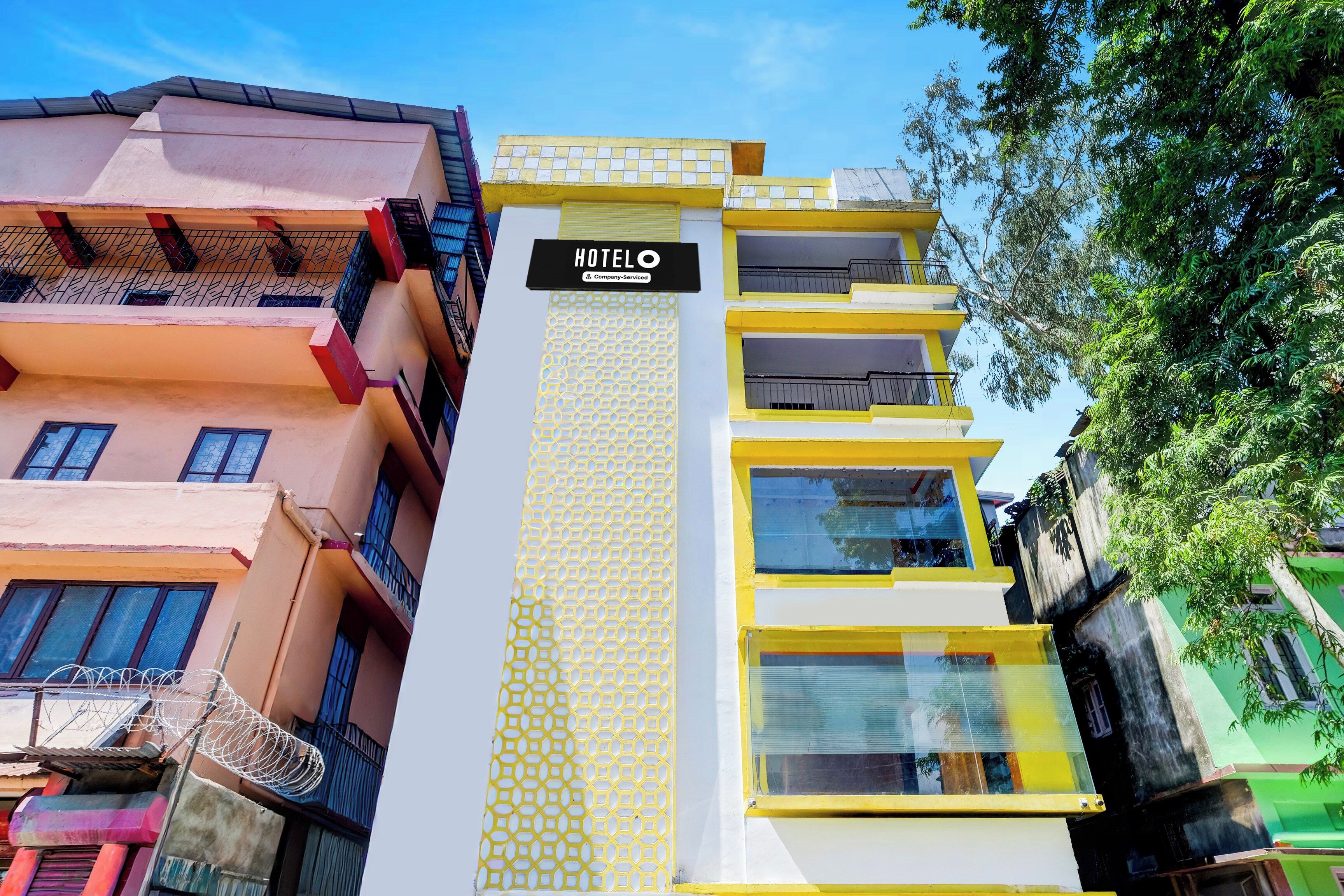 Un immeuble à plusieurs étages, reconnaissable à son grand panneau indiquant « HÔTEL », à ses balcons et à sa façade ornée de motifs.