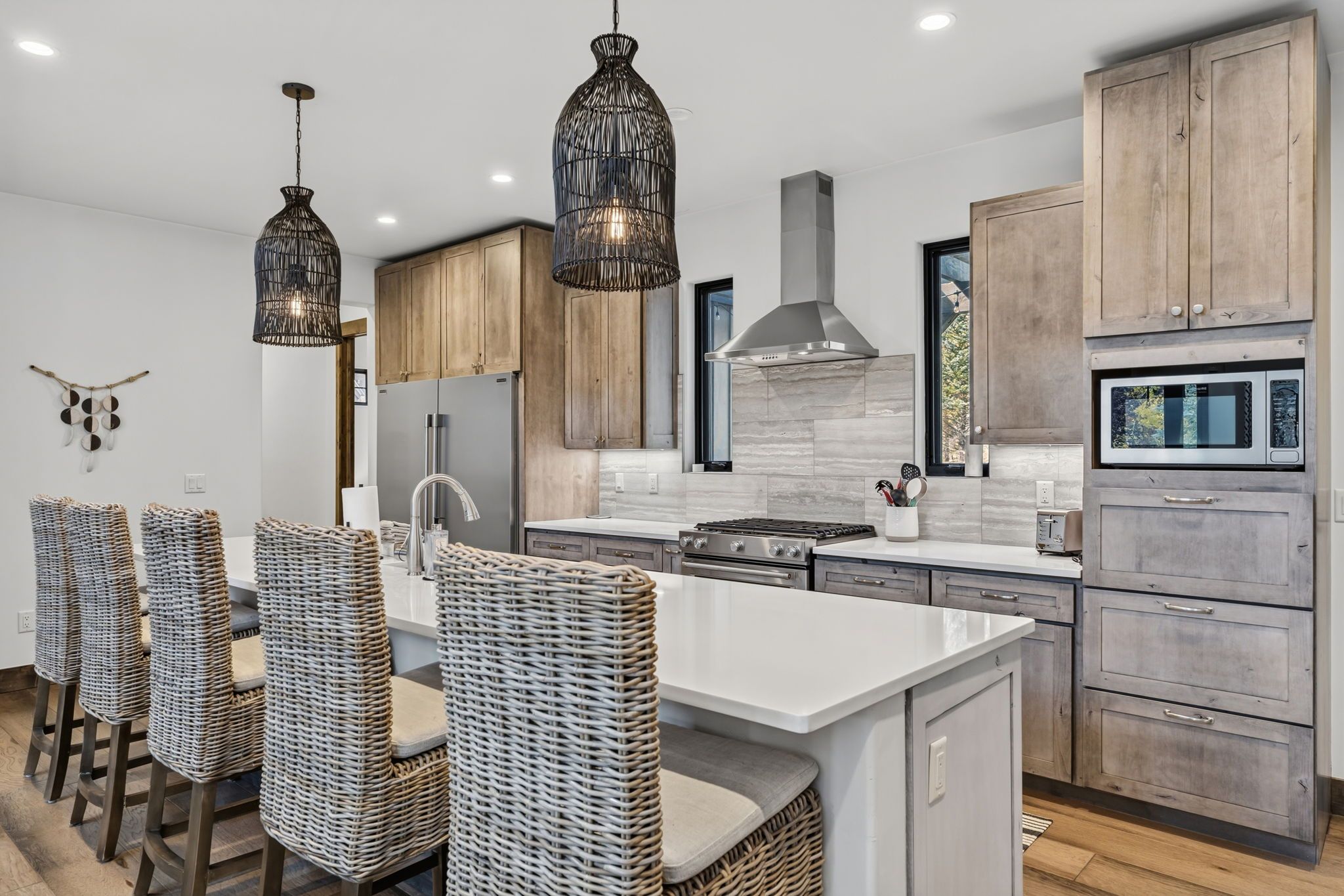A modern kitchen with a central island, wooden cabinets, and a built-in microwave.