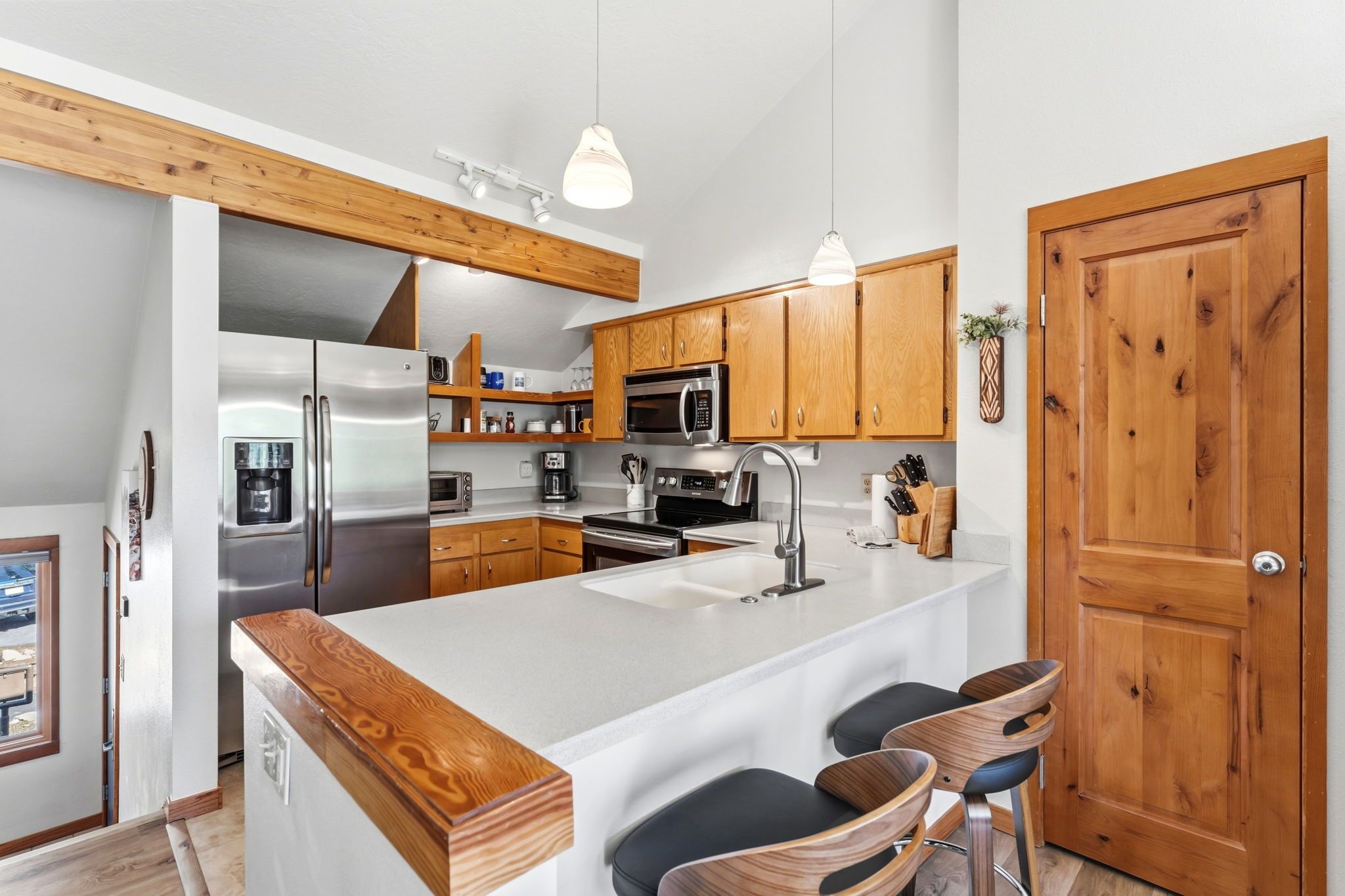 Une cuisine moderne avec des meubles en bois, des appareils en acier inoxydable et un îlot central doté de tabourets de bar.