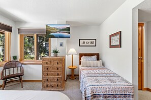 Une chambre à coucher comprenant un lit, une commode, une chaise, une lampe et un téléviseur.