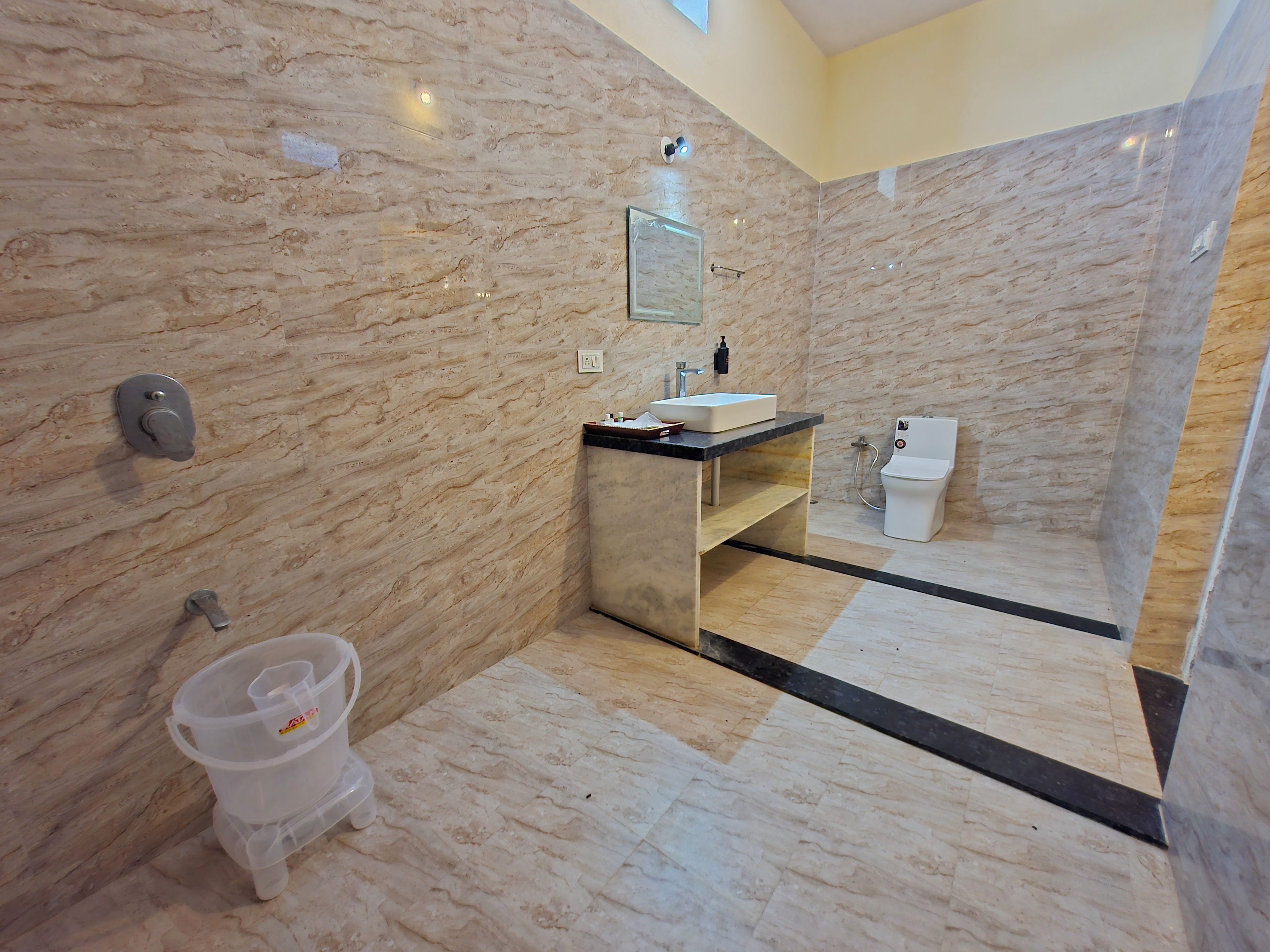 Un baño moderno con paredes de mármol, un lavabo, un inodoro y una ducha.