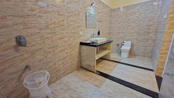 Un baño moderno con paredes de mármol, un lavabo, un inodoro y una ducha.