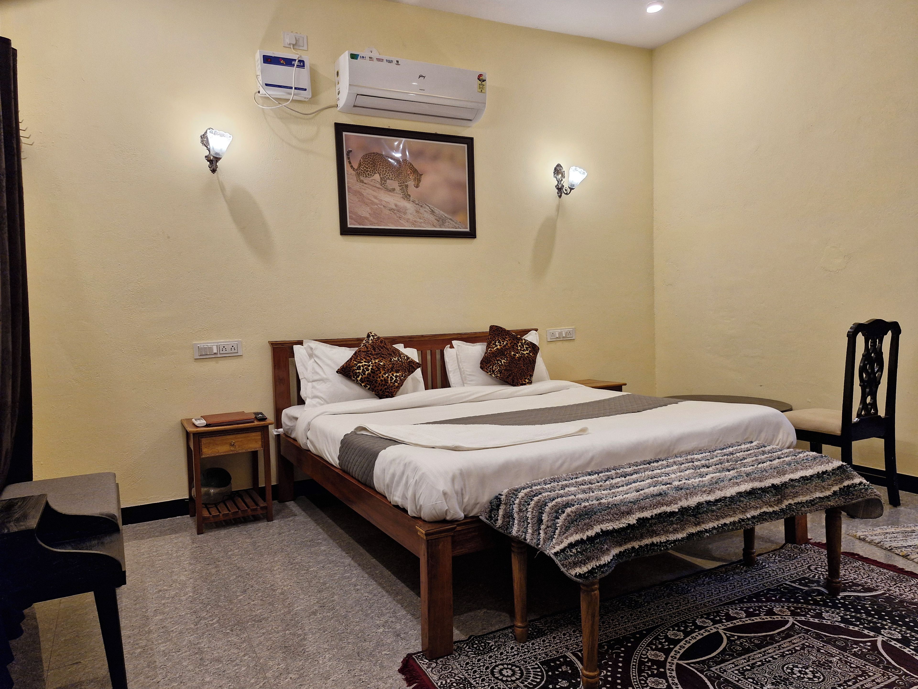 Una habitación de hotel con cama, mesitas de noche, aire acondicionado instalado en la pared y una alfombra.
