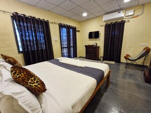 Una habitación de hotel con una cama, un televisor, una silla y un armario.