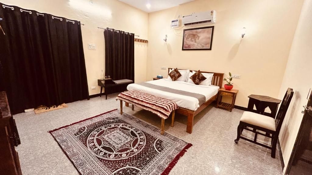 A hotel room with a bed, a chair, a small table, a rug, and an air conditioning unit.