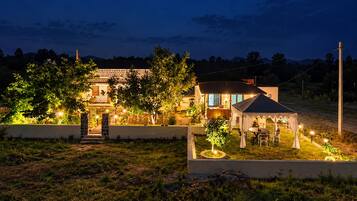 Una casa de piedra luminosa con jardín y una zona de estar cubierta al aire libre.