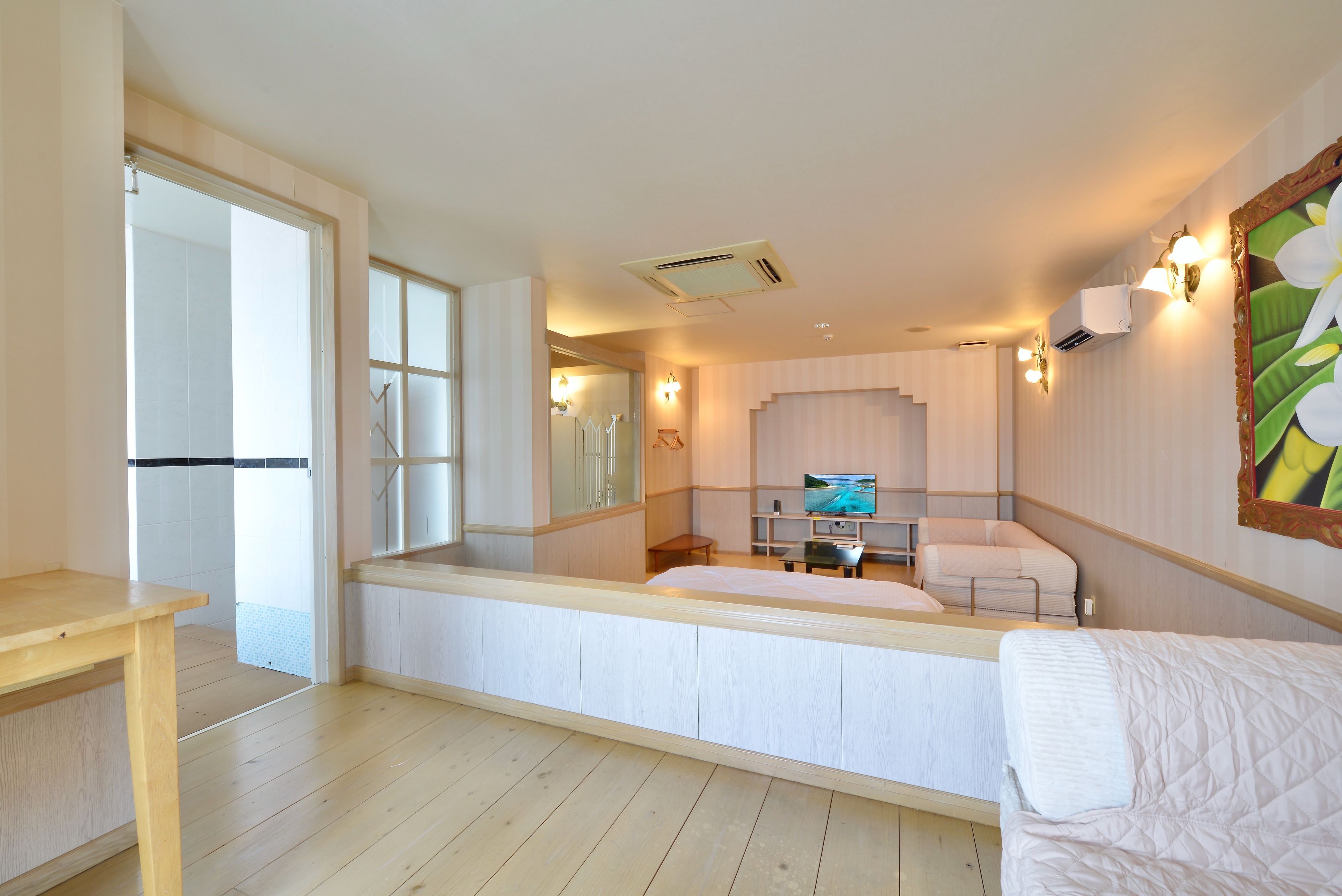 A hotel room with a bed, a TV, a desk, and a large window.
