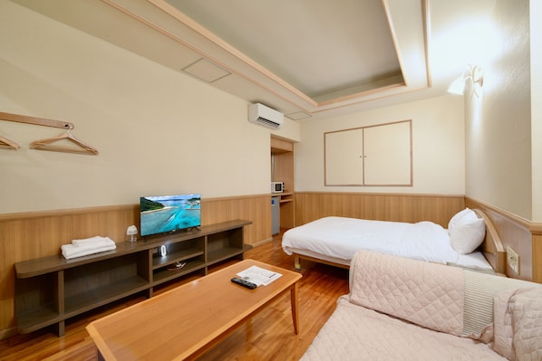 Habitación de hotel con cama, televisión, escritorio y zona de estar.