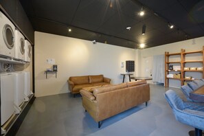 Un interior moderno con un sofá, una mesa y un área de lavandería con lavadoras.