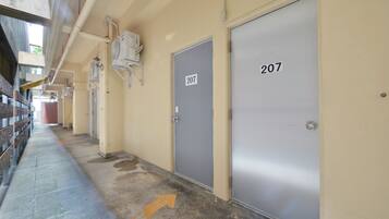 A corridor with doors numbered 207 and 208, a concrete floor with a directional arrow, and overhead pipes.