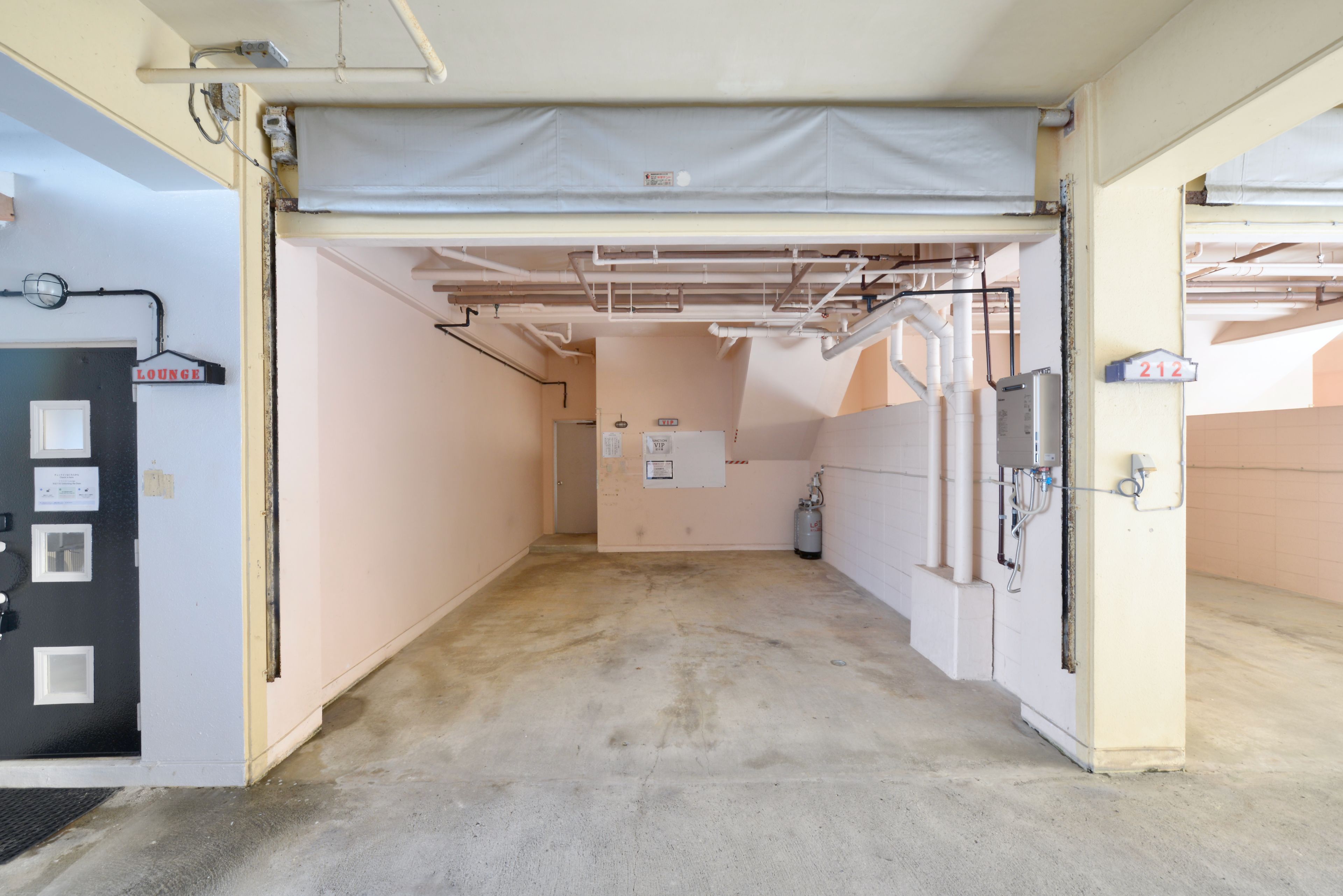 A corridor with a door labeled 'Lounge' on the left, a water heater on the right, and a sign with the number '212' above it.