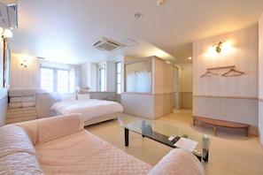 A hotel room with a bed, a sofa, a glass table, a wardrobe, and a mirror. - Hotel JUNCTION  (Okinawa-shi)