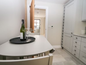 A dining area with a table, a wine bottle, and a glass. - The Granary (Bordon)