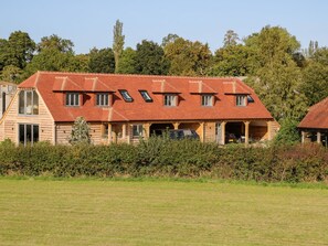 A large house with a sloped roof, multiple windows, and a garage. - The Granary (Bordon)