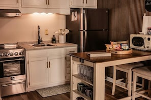Een moderne keuken met roestvrijstalen apparatuur, een houten eiland en een bord met informatie voor gasten.