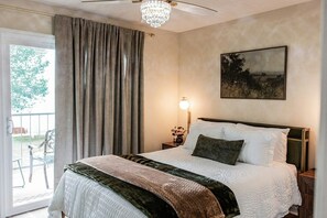 A bedroom with a large bed, a chandelier, a painting, and a view of the outdoors. - Cozy, newly renovated, one bedroom apartment in Kingston,  TN (Kingston)