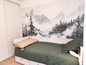 Ein Schlafzimmer mit Bett, Fenster und einer Wandmalerei von einer Berglandschaft.