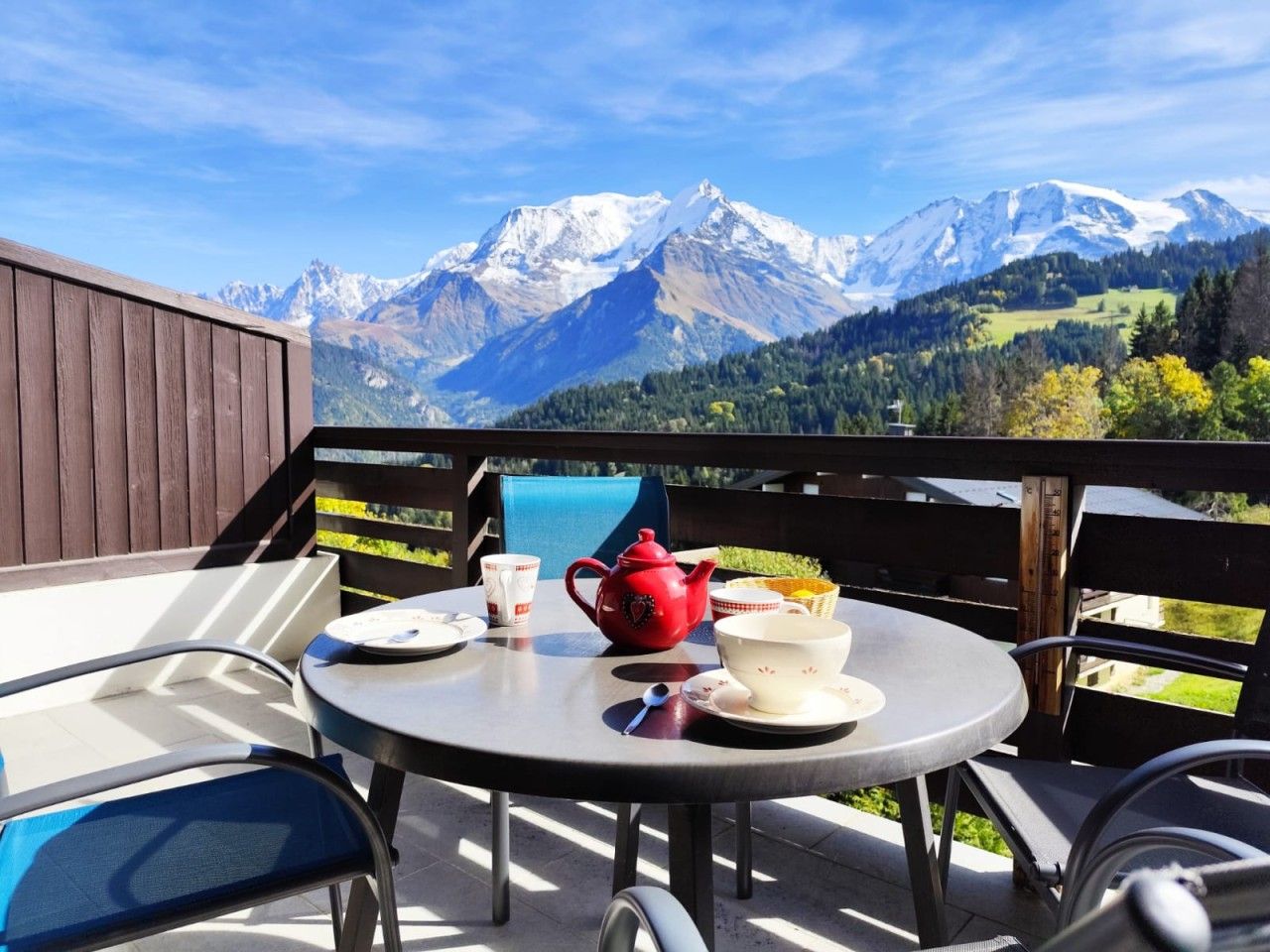 Une terrasse avec une table préparée pour le thé, d’où l’on peut admirer une chaîne de montagnes.