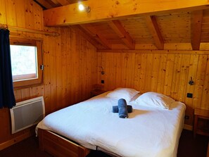 Een houten kamer met een bed, een raam en een verwarming.