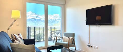Un salon moderne avec un canapé, un fauteuil et un téléviseur fixé au mur.