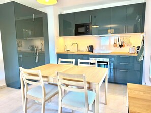 A modern kitchen with dark cabinets, a microwave, and a wooden dining table with chairs. - La Belle Vue (4 people) Terrace with a view of the mountains. Indoor parking (Saint-Gervais-les-Bains)