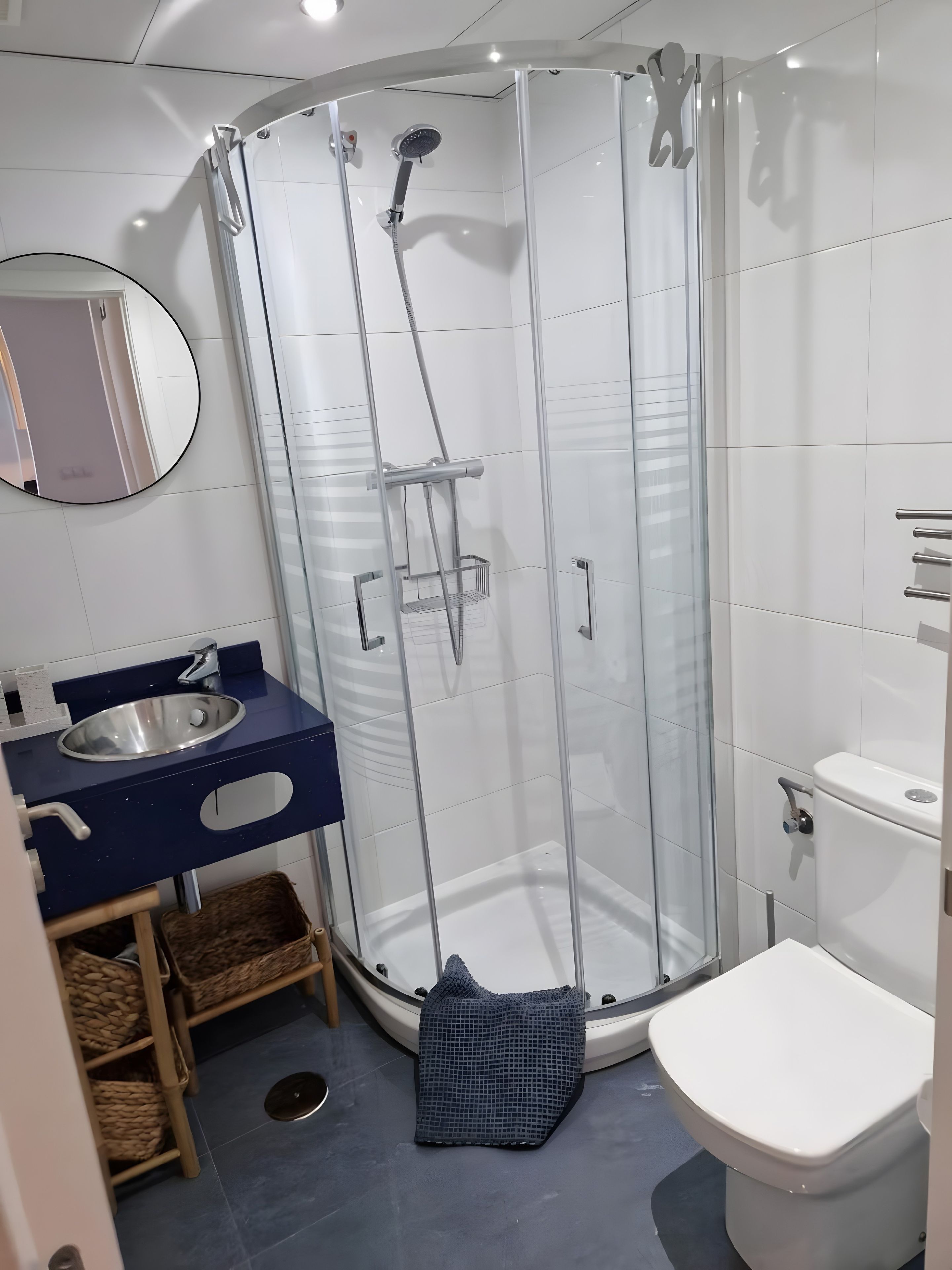 Uma casa de banho moderna com cabine de duche em vidro, lavatório com espelho e sanita.