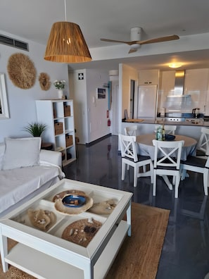 En moderne stue med sofa, sofabord og spiseplads.