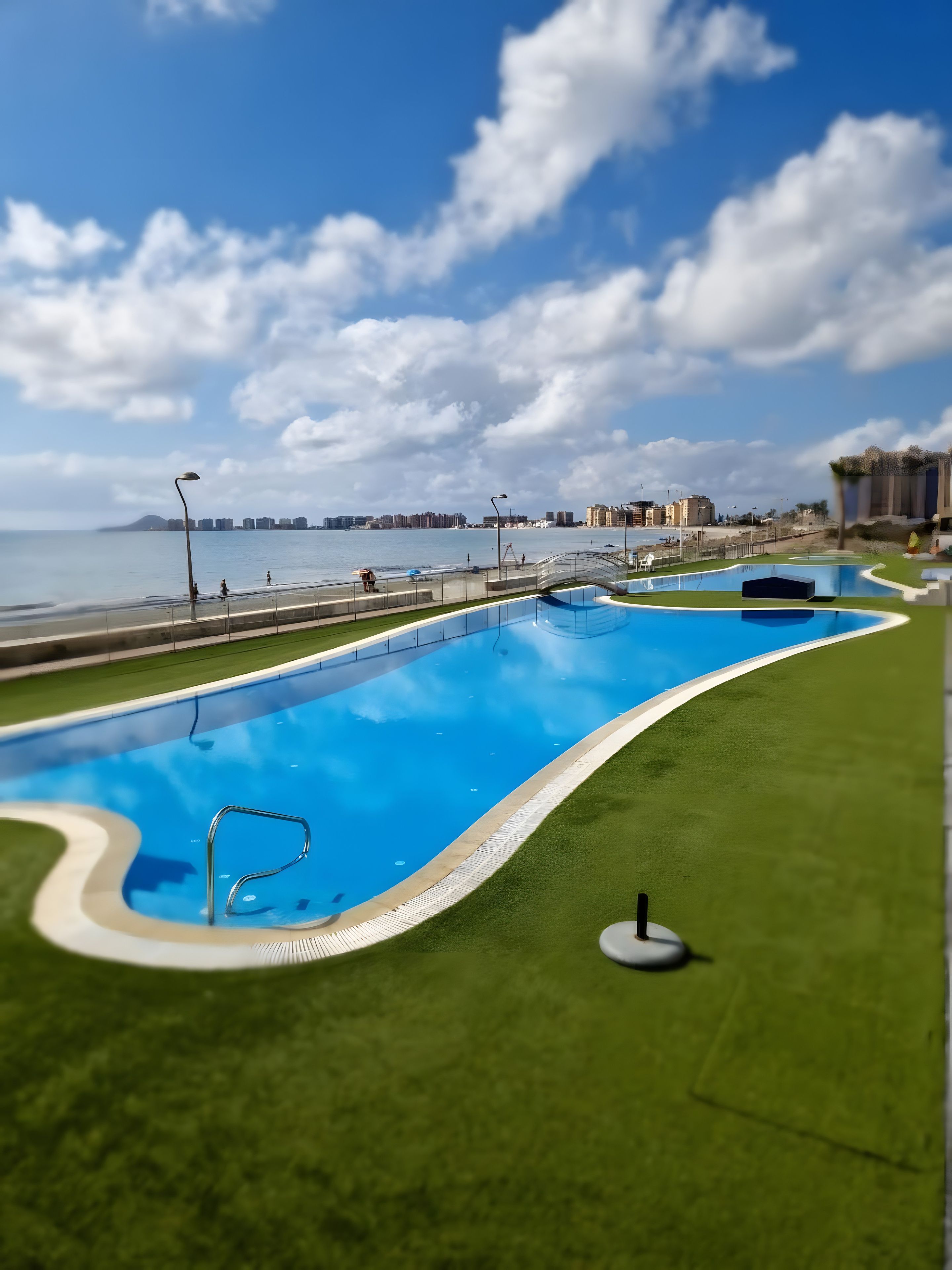 A swimming pool with a view of the sea and buildings in the background.