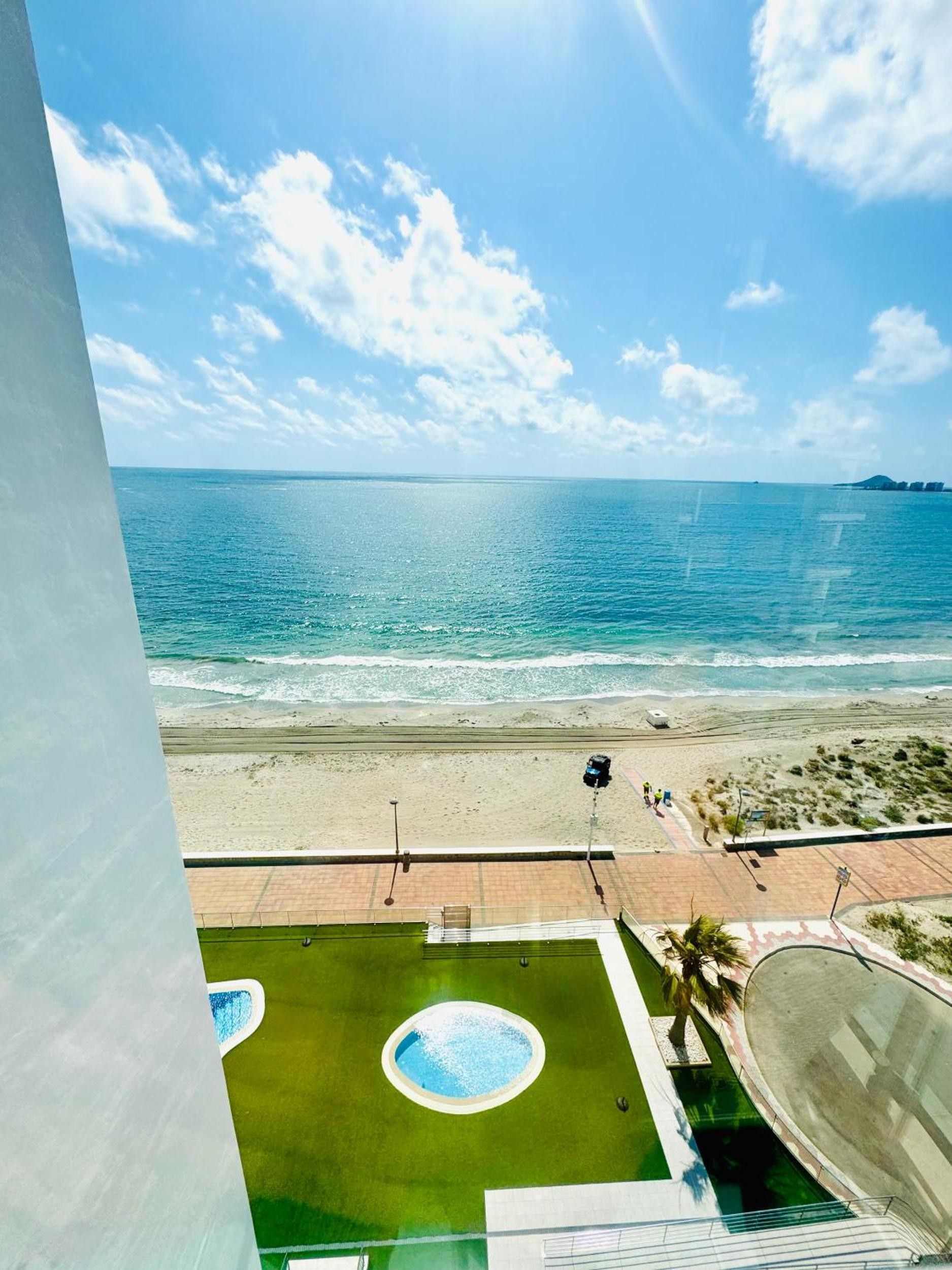 Blick auf einen Strand mit Poolbereich, klarem Himmel und dem Meer.