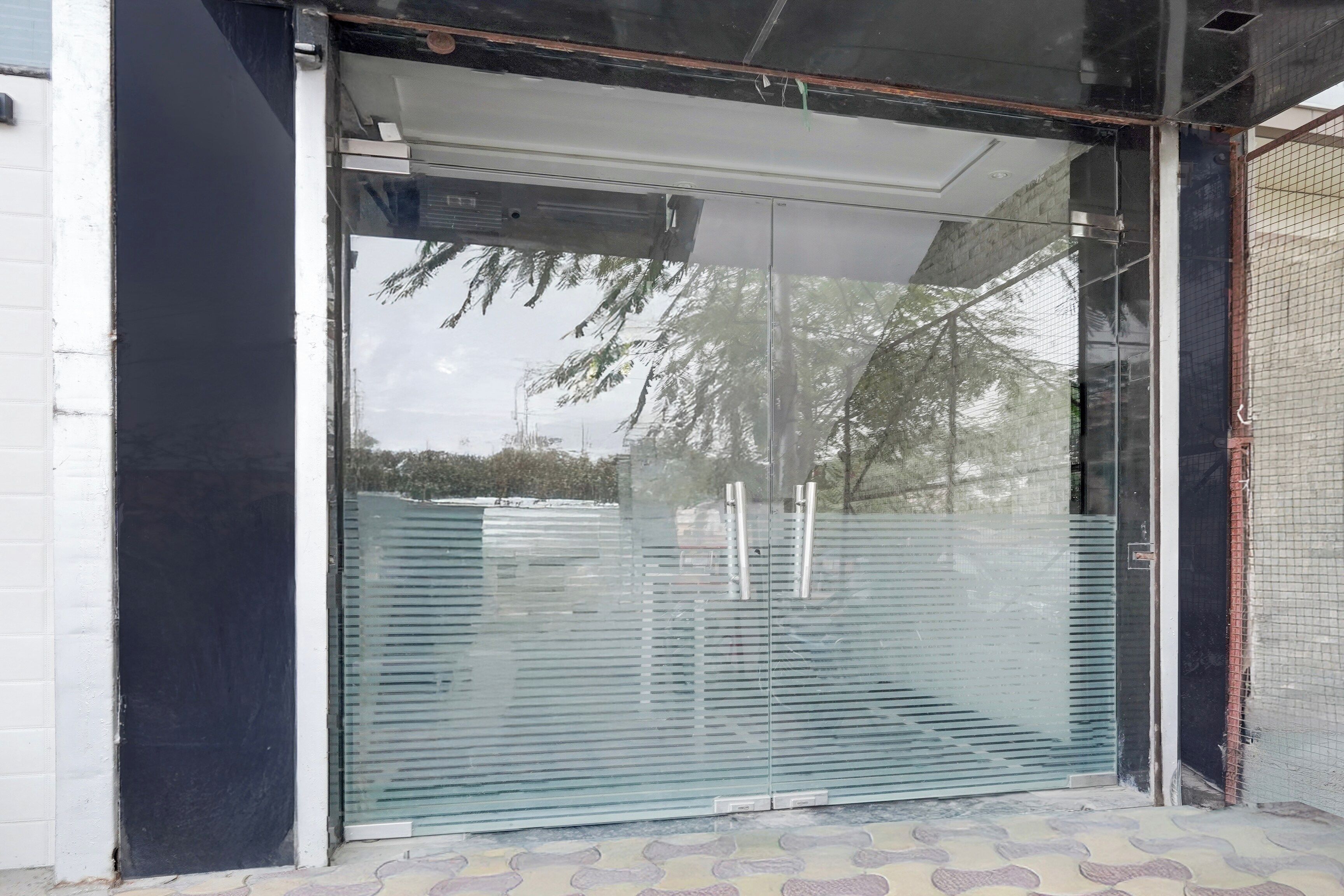 Une entrée moderne, avec une porte en verre et un portail en métal.