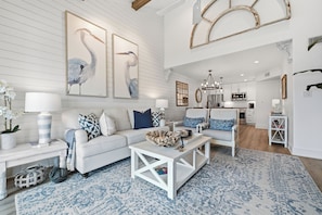 A spacious living room with a white sofa, a coffee table, and a patterned rug. - The Lady Cora | Canal Views + Community Pool (Rockport)