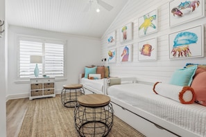 A room with a white bed, a small table, a lamp, and wall art. - The Lady Cora | Canal Views + Community Pool (Rockport)